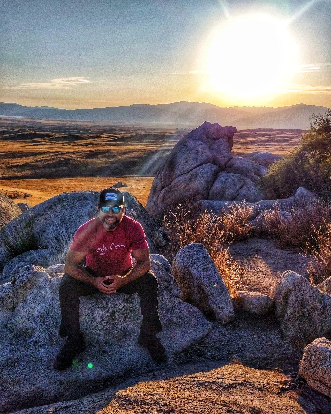 A seated hiker among rocks at sunrise