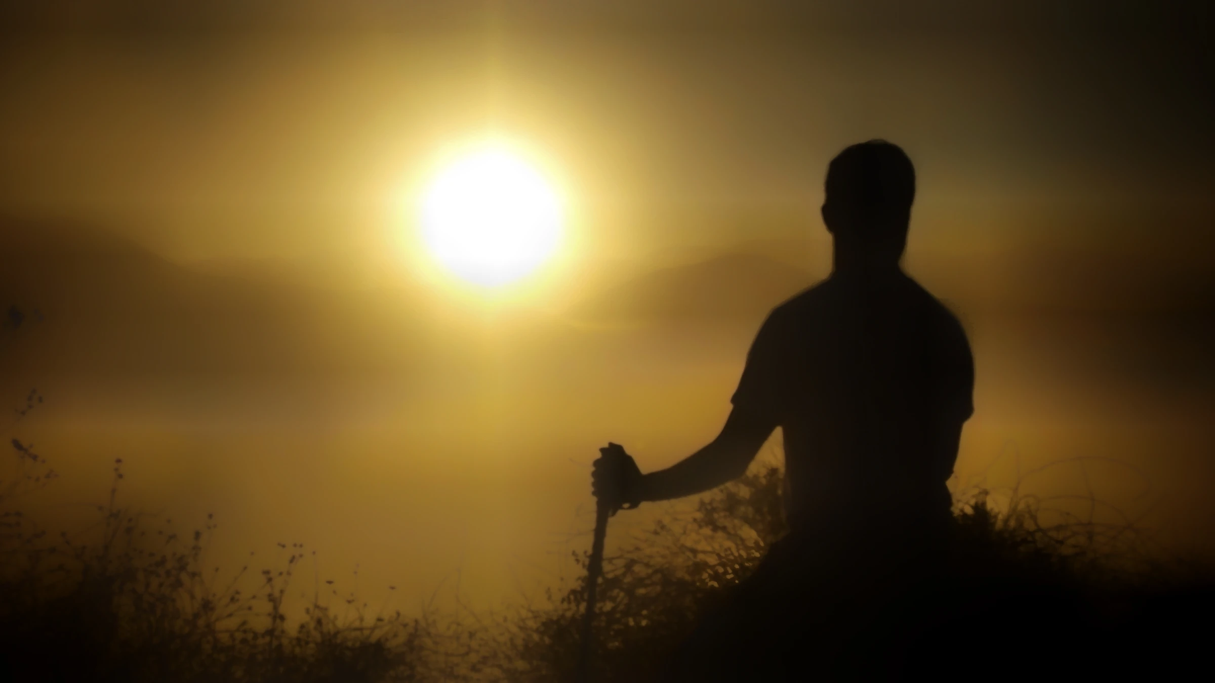 A silhouetted hiker against a warm mountain sunset