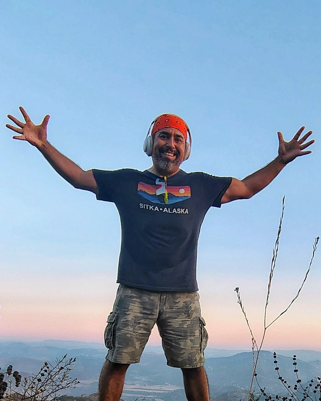 A hiker standing with arms open beneath a wide sky